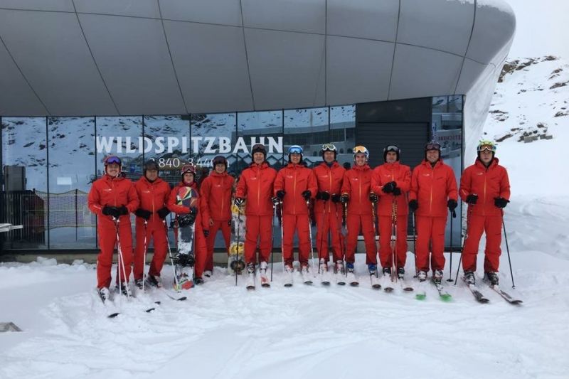 Skilehrerteam in roten Anzügen vor der Wildspitzbahn